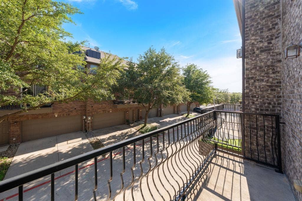 Elevated balcony featuring custom black wrought-iron railings and concrete flooring, set against a multi-story brick exterior