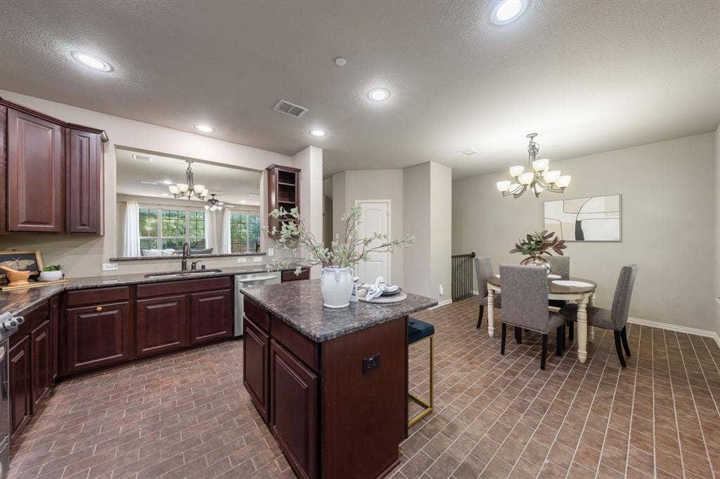Kitchen featuring dark-finish cabinetry, stone-texture countertops, center island, brick-patterned tile flooring, and recessed ceiling lighting
