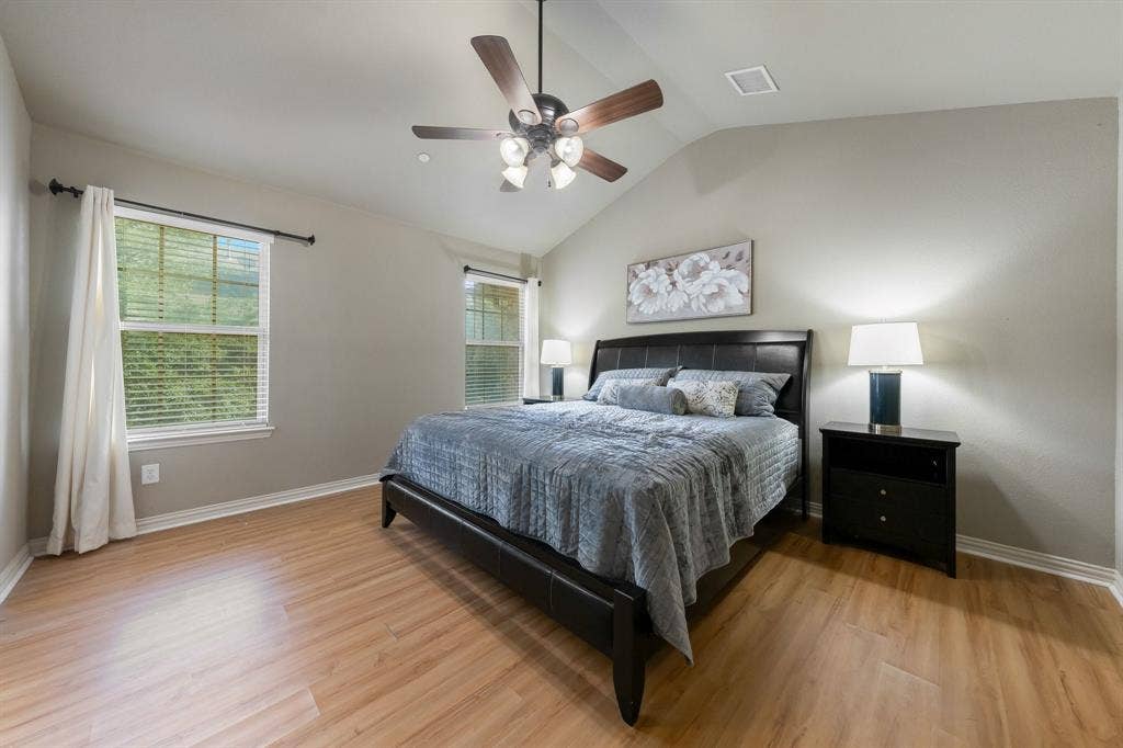 Vaulted ceiling featuring a central multi-blade ceiling fan and wood-finish flooring throughout