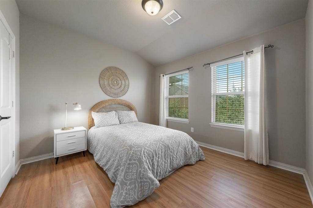 Room featuring wood-finish flooring, neutral wall paint, and dual windows
