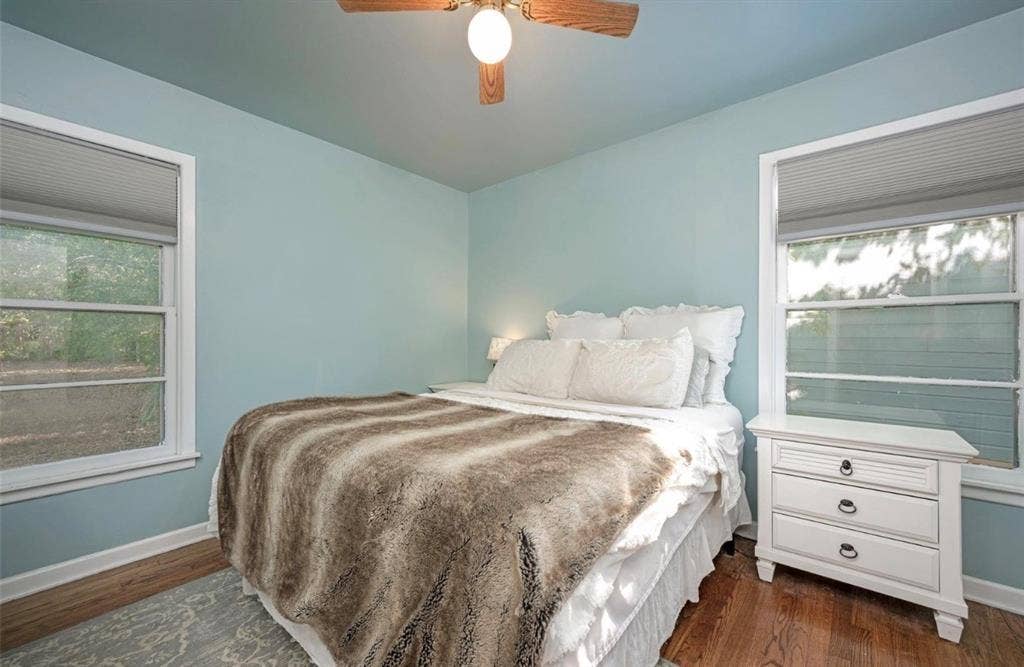 Room featuring wood-finish flooring, dual windows with pleated shades, and a ceiling-mounted light fixture