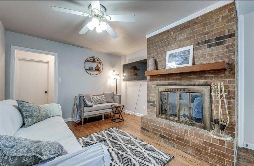 Floor-to-ceiling brick fireplace with a wood mantel, brass-framed glass screen, wood-finish flooring, and a ceiling-mounted light fixture
