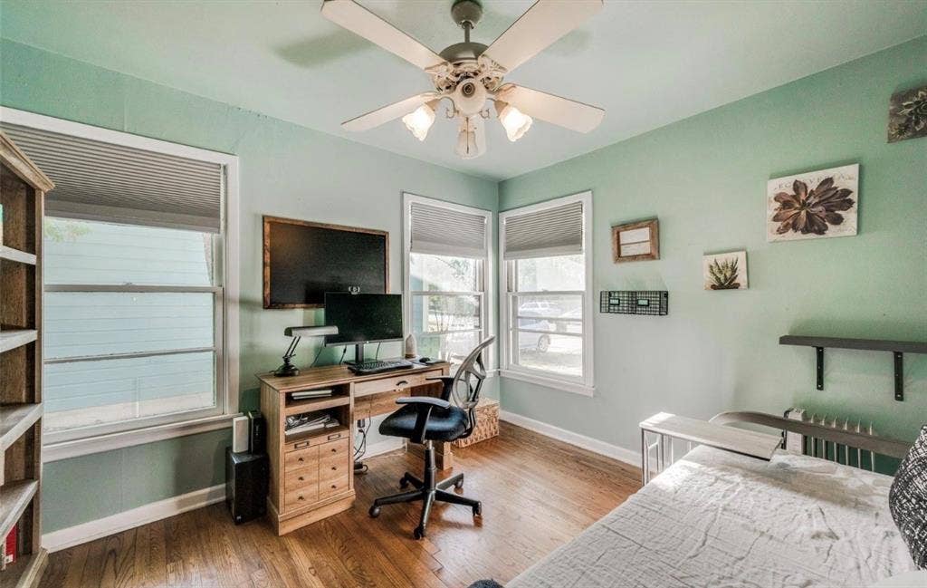 Wood-finish flooring, multi-pane windows with integrated blinds, and a ceiling-mounted fan with light fixture
