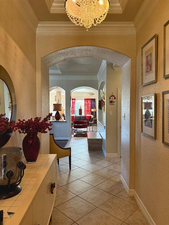 416 Wooded Creek Avenue, Wylie, TX 75098 Foyer featuring a recessed tray ceiling, crystal chandelier, arched architectural entryways, and tile flooring
