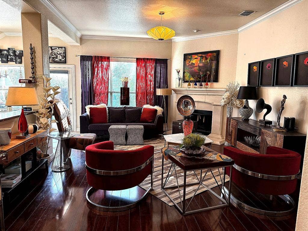 416 Wooded Creek Avenue, Wylie, TX 75098 Living space featuring wood-finish flooring, crown molding, and a stone-surround fireplace with an integrated mantel