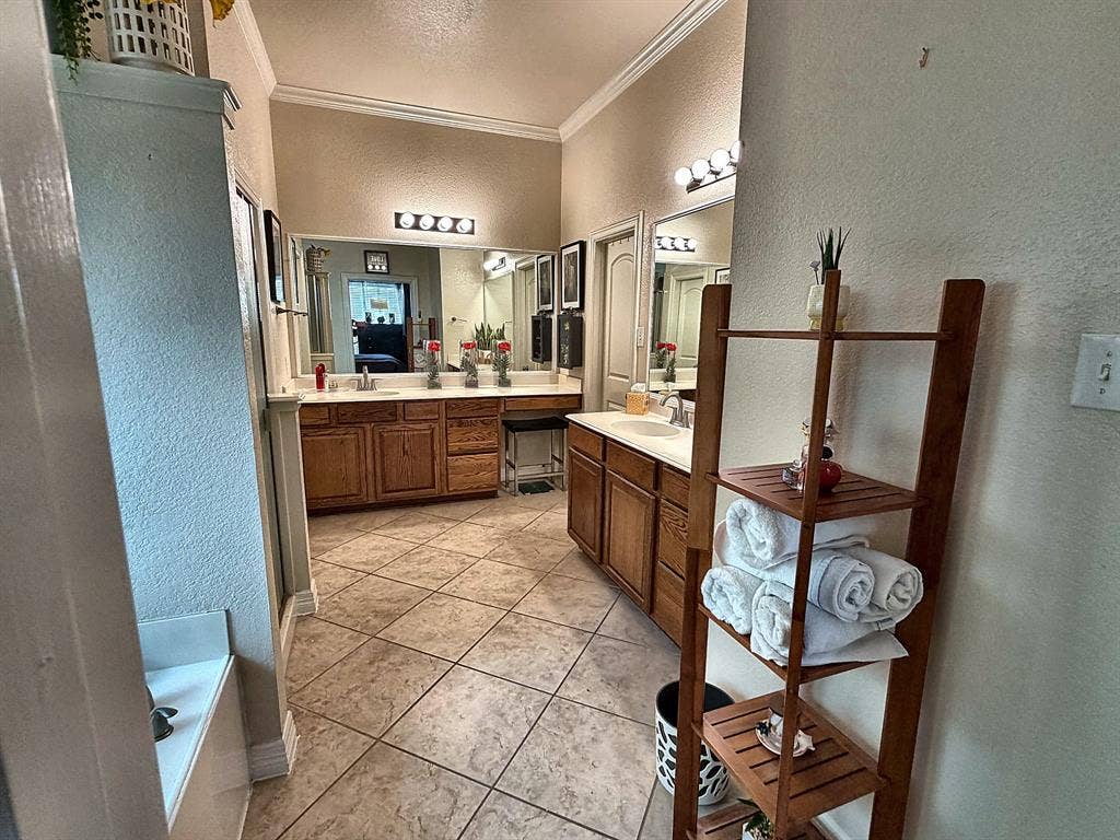 416 Wooded Creek Avenue, Wylie, TX 75098 Dual-vanity bathroom featuring wood-finish cabinetry, tile flooring, crown molding, and expansive wall-mounted mirrors