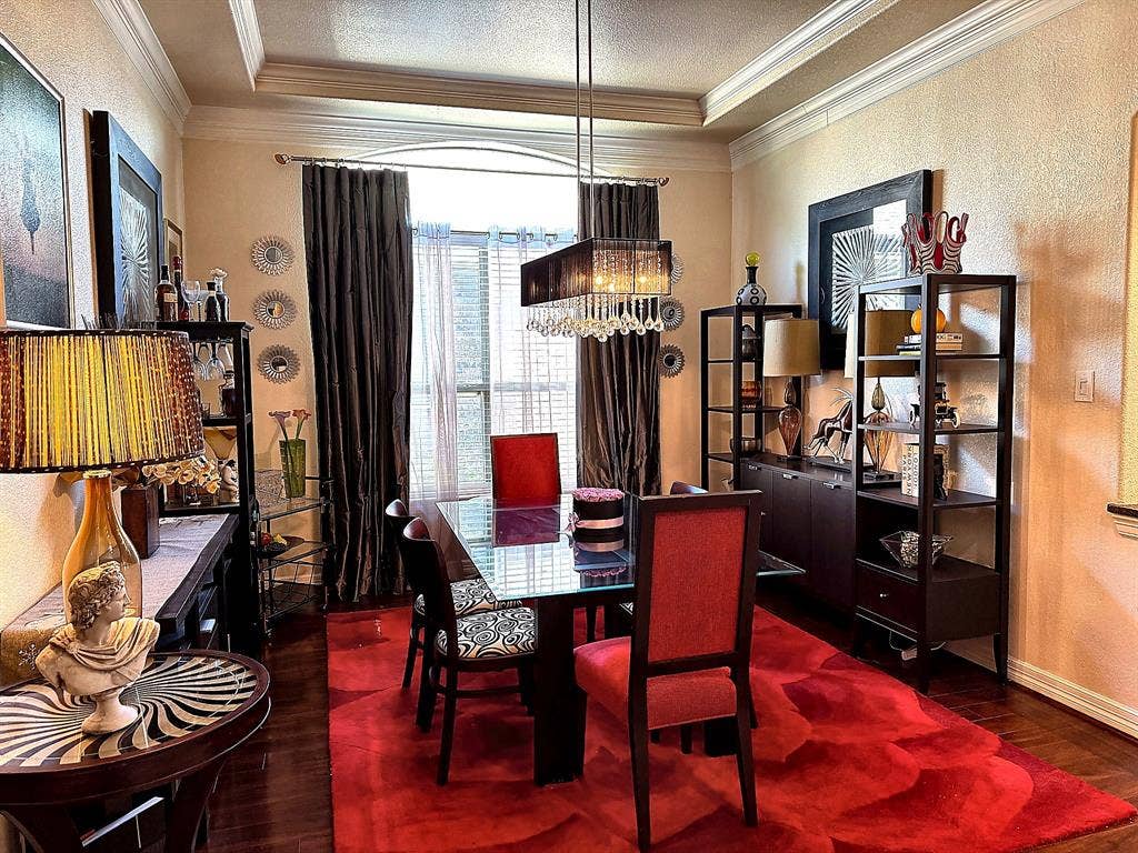 416 Wooded Creek Avenue, Wylie, TX 75098 Dining room featuring dark wood-finish flooring, recessed tray ceiling with crown molding, and a rectangular, multi-tiered crystal pendant light fixture