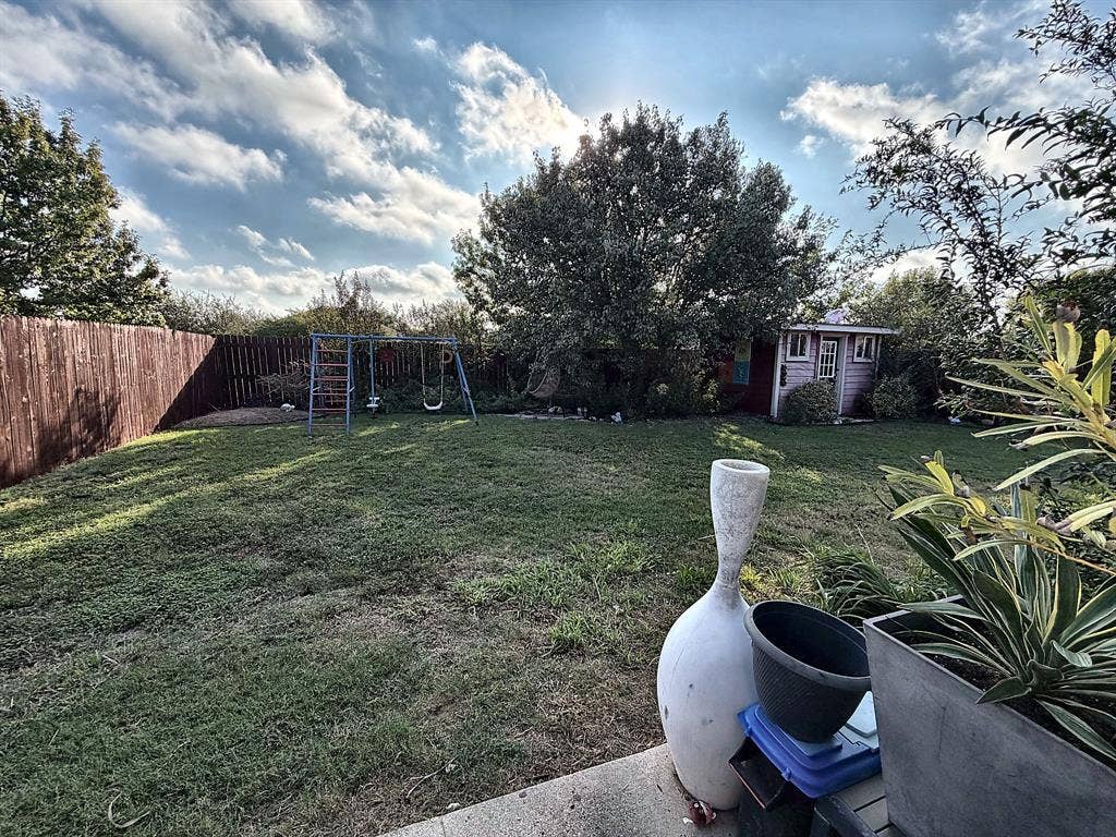 416 Wooded Creek Avenue, Wylie, TX 75098 Expansive backyard featuring a level lawn, perimeter wood fencing, mature trees, and a detached outbuilding