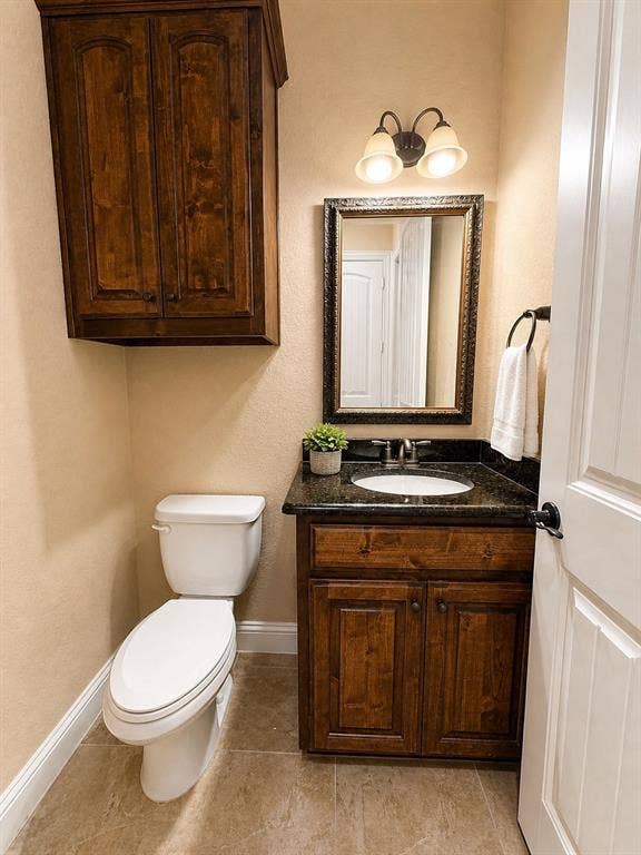 13812 Nash Lane, Frisco, TX 75035 Bathroom vanity with dark wood cabinetry and a dark stone countertop featuring an undermount sink