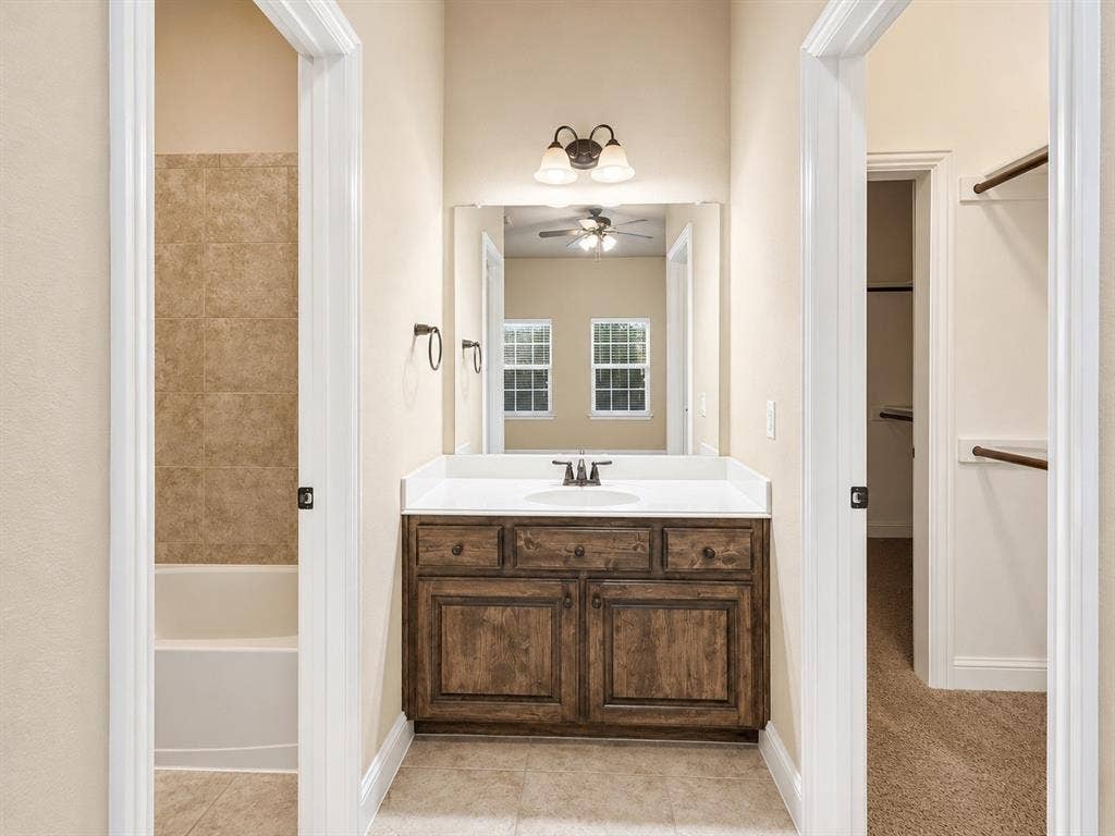 13812 Nash Lane, Frisco, TX 75035 Bathroom vanity with a white countertop and integrated sink, complemented by a wood-finish cabinet with dark hardware