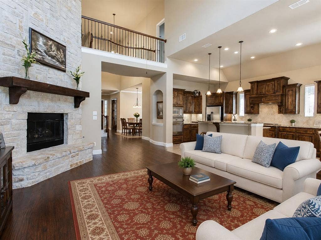 13812 Nash Lane, Frisco, TX 75035 Two-story living area with a stone fireplace, wood-finish flooring, and an upper-level balcony