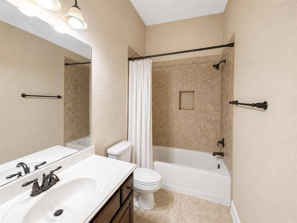 13812 Nash Lane, Frisco, TX 75035 Bathroom featuring a white vanity with an integrated sink, dark bronze fixtures, and an expansive wall mirror
