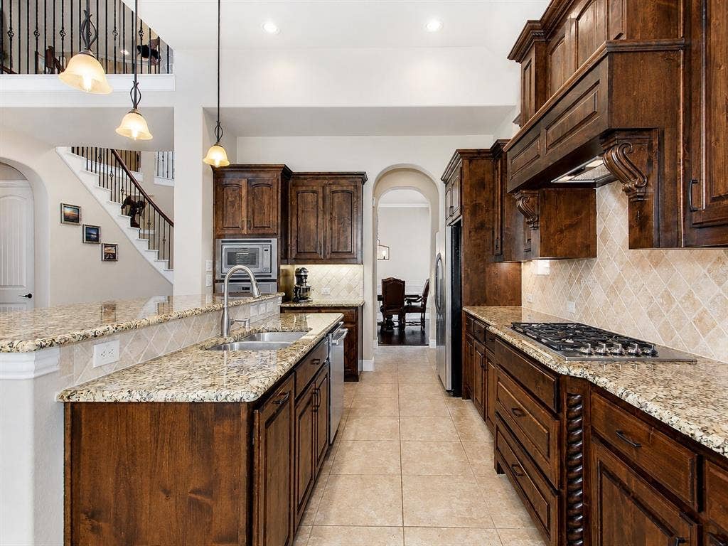 13812 Nash Lane, Frisco, TX 75035 Gourmet kitchen featuring custom wood cabinetry, granite countertops, a gas cooktop, built-in appliances, and tile flooring