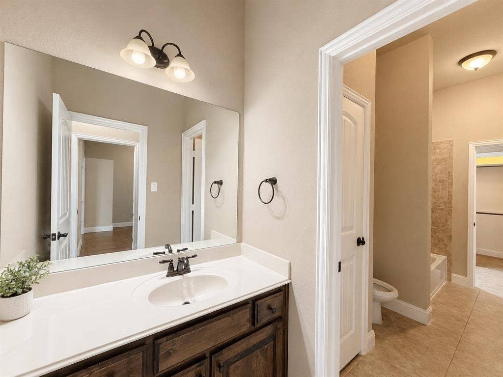 13812 Nash Lane, Frisco, TX 75035 Bathroom vanity featuring a single sink with a dark bronze faucet, a white countertop, and a dark wood cabinet