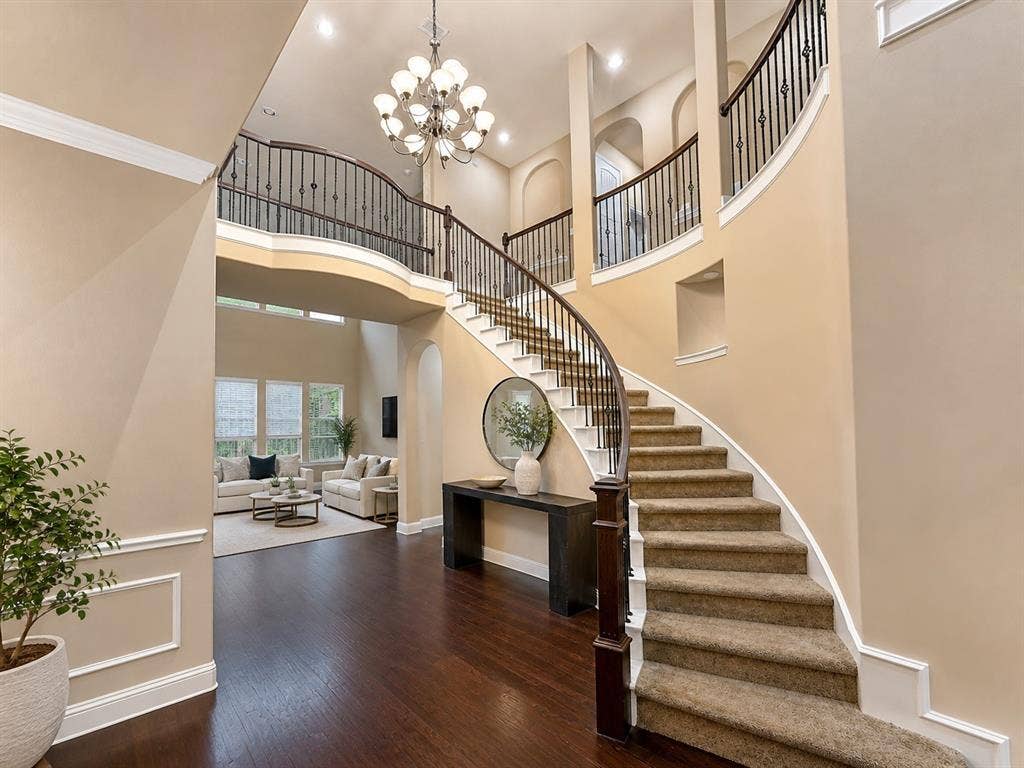 13812 Nash Lane, Frisco, TX 75035 Grand entryway featuring a curved staircase with carpeted treads and wrought iron balusters