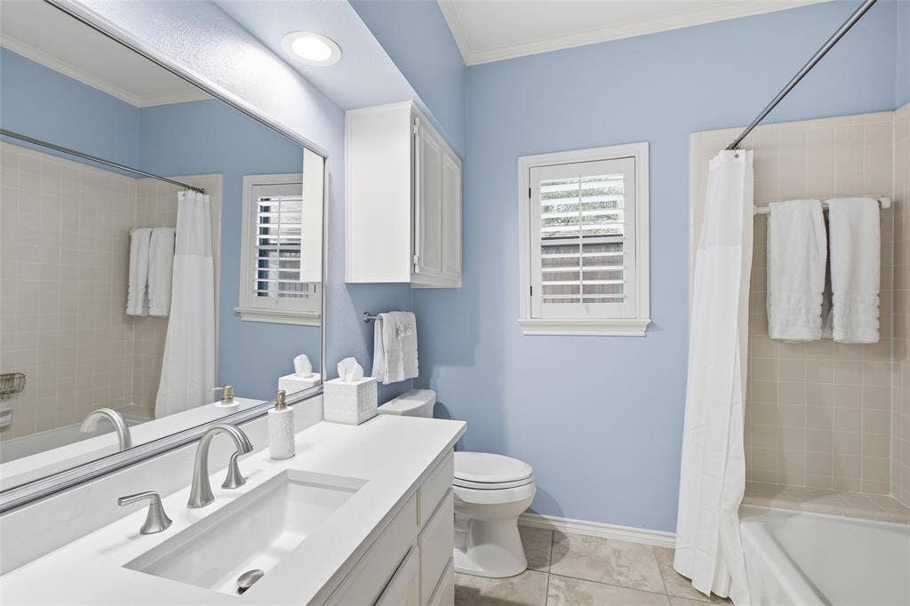 4115 Brooktree Lane, Dallas, TX 75287 Hall bath with a quartz vanity, plantation shutter, and a calming blue palette.