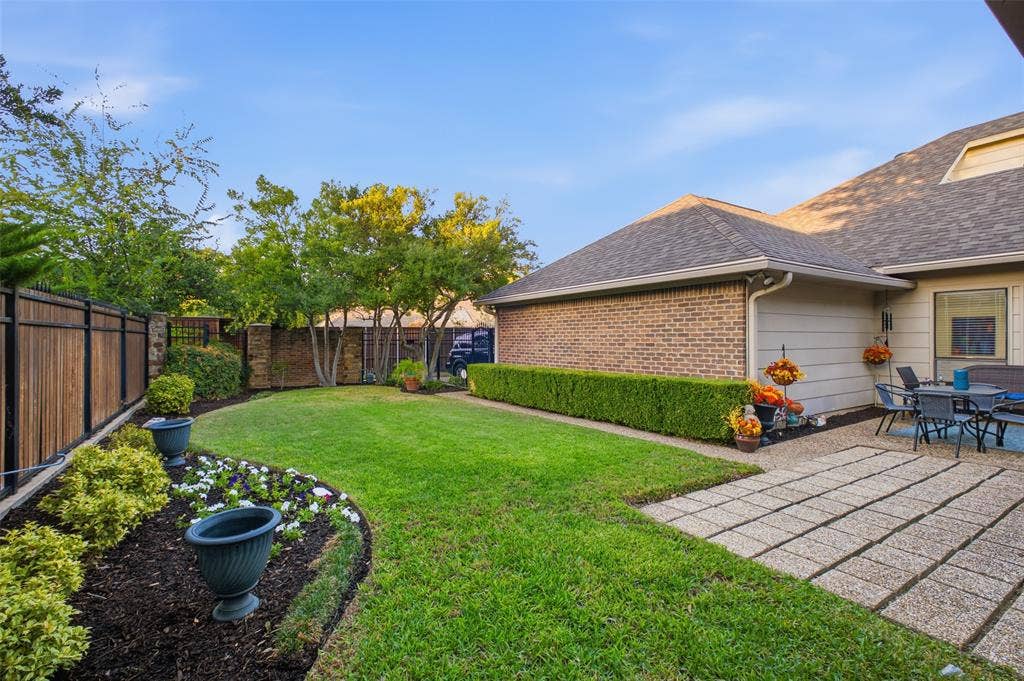 4115 Brooktree Lane, Dallas, TX 75287 A green, private backyard enclosed by a wood-and-iron fence with stone columns—your own backyard escape.
