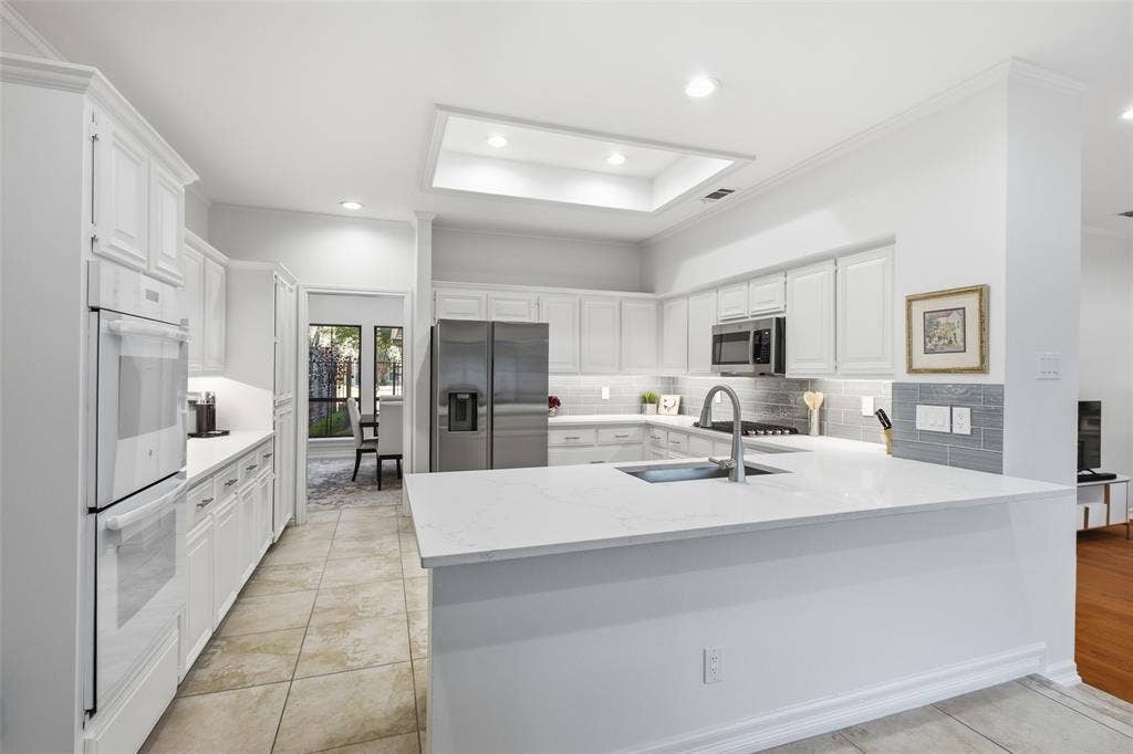 4115 Brooktree Lane, Dallas, TX 75287 Double wall ovens, abundant white cabinetry, and a sprawling quartz peninsula give the home chef room to create.