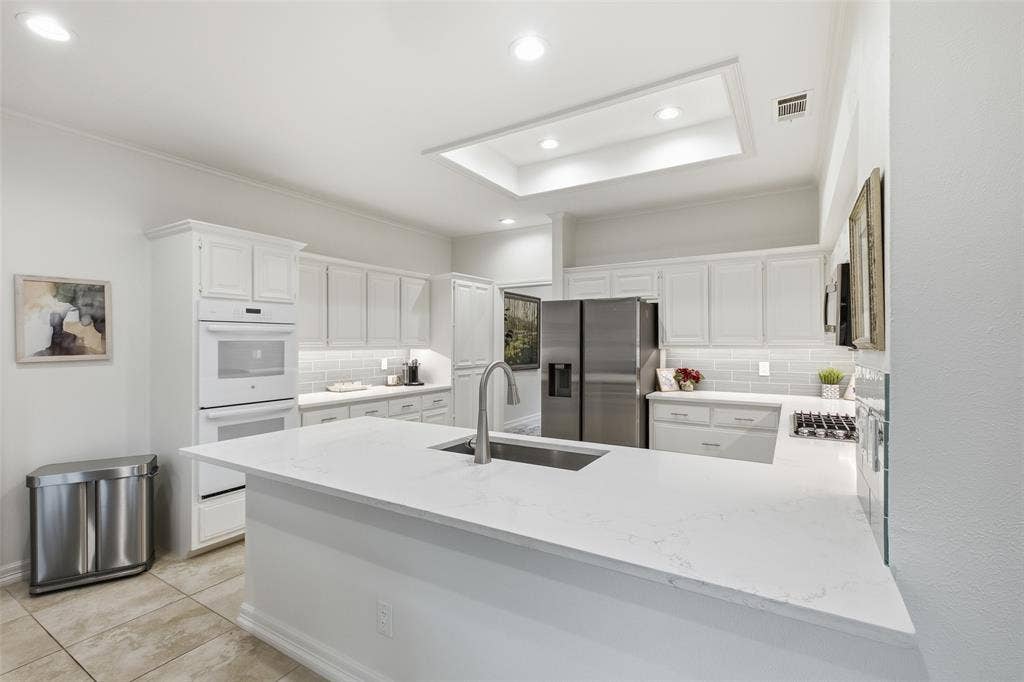 4115 Brooktree Lane, Dallas, TX 75287 Quartz countertops, gray subway tile, and a lighted tray ceiling—a kitchen as pretty as it is practical.