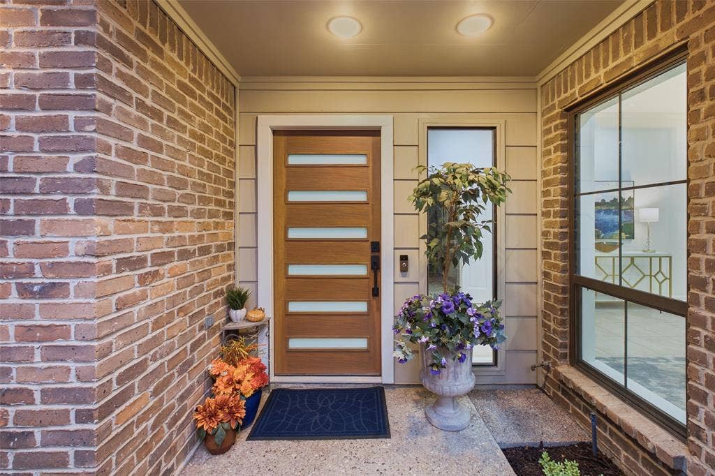 4115 Brooktree Lane, Dallas, TX 75287 A modern wood-and-glass front door with sidelight sets a fresh, stylish tone at the covered front entry.