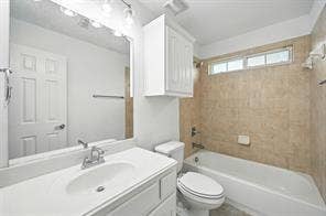 Bathroom featuring a vanity with a white countertop and oval sink, a wall-mounted storage cabinet, a large mirror, and a tile-surround bathtub