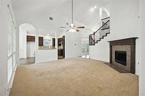 Vaulted ceilings, open-concept floor plan, fireplace with tile surround, arched architectural details, and decorative metal staircase railings