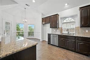 Kitchen featuring dark cabinetry, stone countertops, stainless steel dishwasher, vaulted ceiling, and an arched window