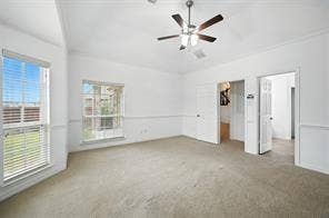 High-ceilinged room featuring neutral carpeting, chair rail molding, two multi-pane windows with fitted blinds, and a central ceiling fan with integrated lighting