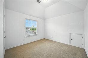 Vaulted ceiling, neutral wall-to-wall carpeting, single-pane window, and built-in access panel