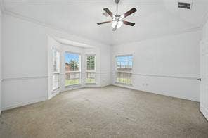 Tray ceiling featuring a central multi-blade ceiling fan with integrated lighting, expansive bay window, and chair rail molding