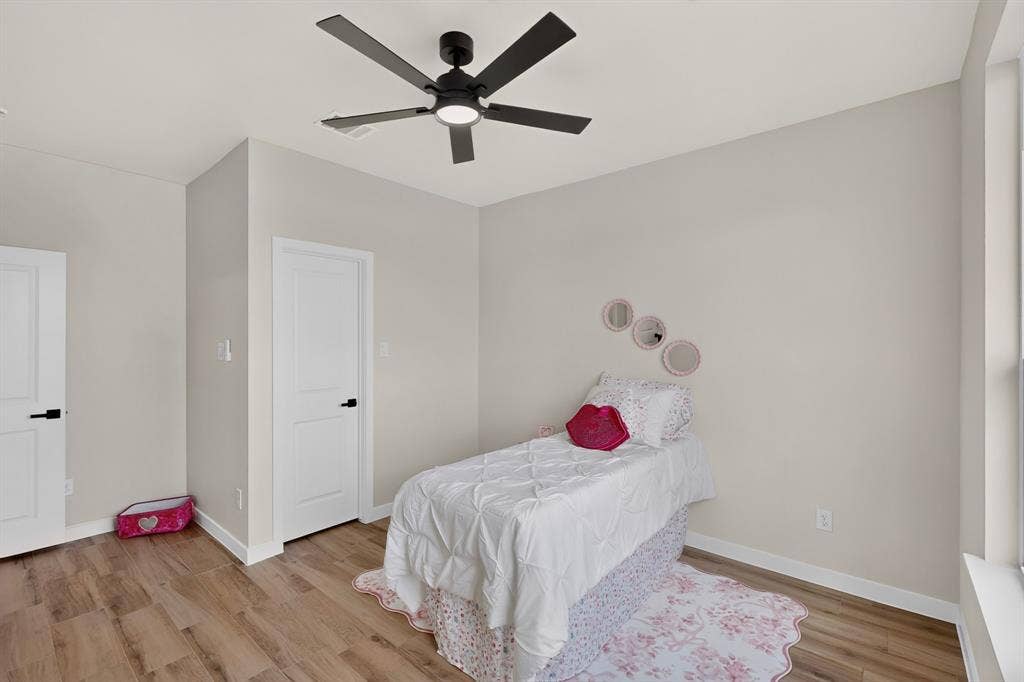 102 Nicklaus Drive, Sulphur Springs, TX 75482 Neutral-toned interior featuring wood-finish flooring, matte black hardware on paneled doors, and a central ceiling fan with an integrated light fixture