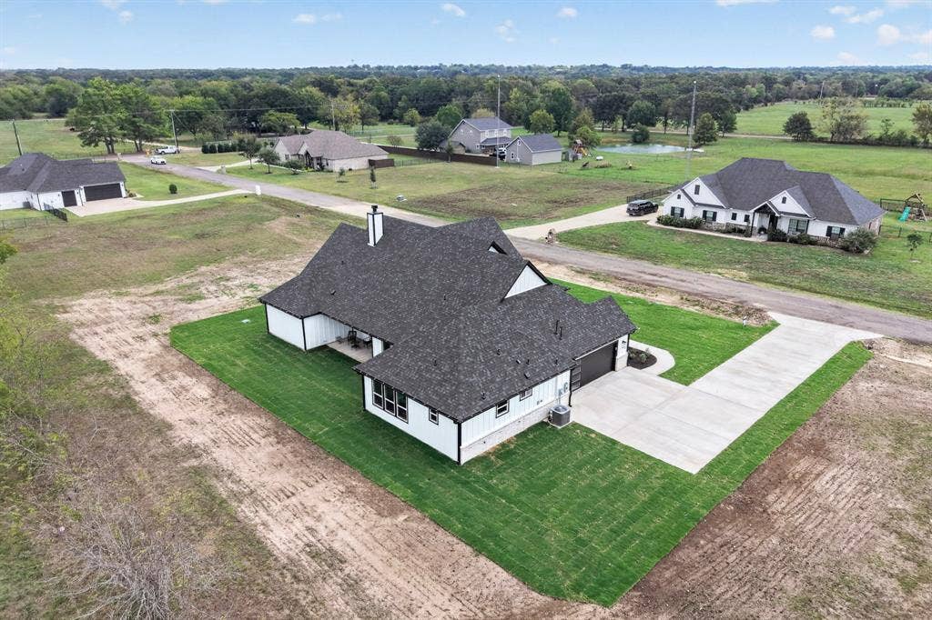 102 Nicklaus Drive, Sulphur Springs, TX 75482 Multi-gabled roofline with shingle finish, white exterior siding, concrete driveway, and manicured lawn