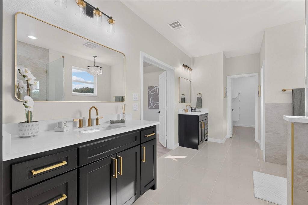 102 Nicklaus Drive, Sulphur Springs, TX 75482 Dual-vanity bathroom featuring matte black cabinetry, gold-toned hardware, quartz countertops, rectangular undermount sinks, and a framed vanity mirror with integrated lighting