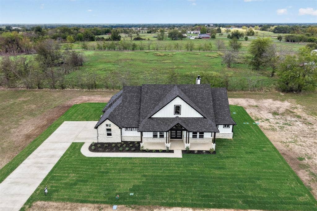 102 Nicklaus Drive, Sulphur Springs, TX 75482 Contemporary architectural exterior featuring a combination of light-toned stone masonry and vertical siding, a multi-gabled dark shingle roof, a covered front porch, and a concrete driveway