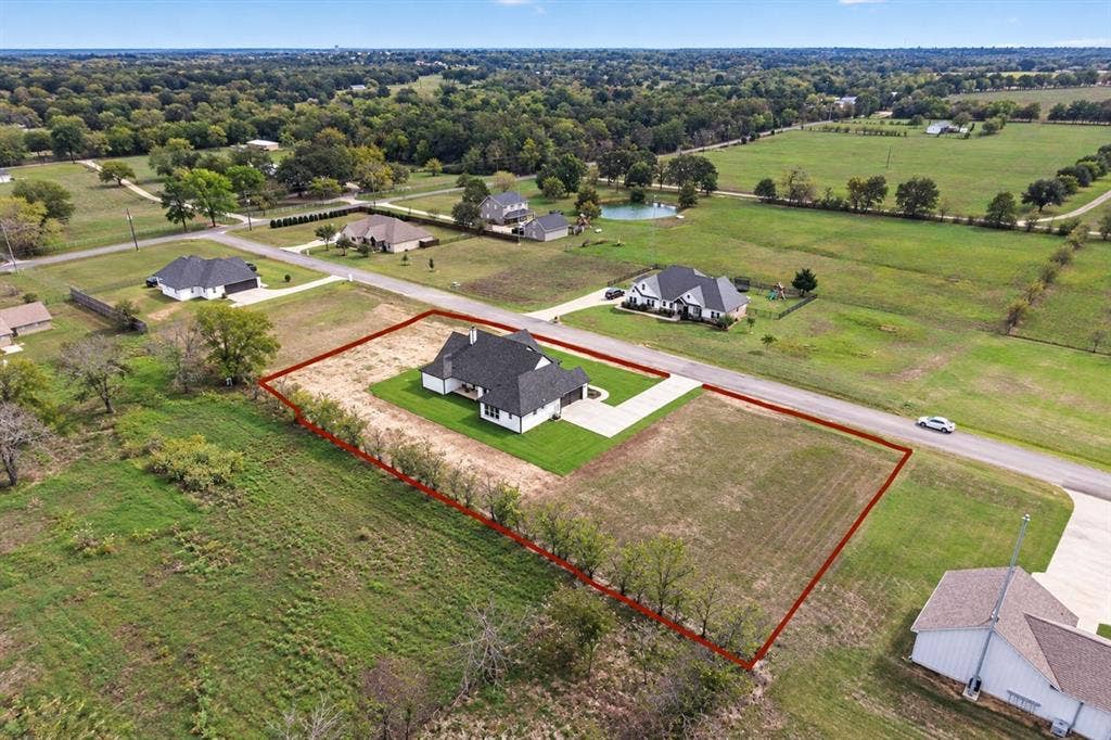 102 Nicklaus Drive, Sulphur Springs, TX 75482 Aerial view of property featuring a multi-gable roofline, attached side-entry garage, paved concrete driveway, and expansive acreage
