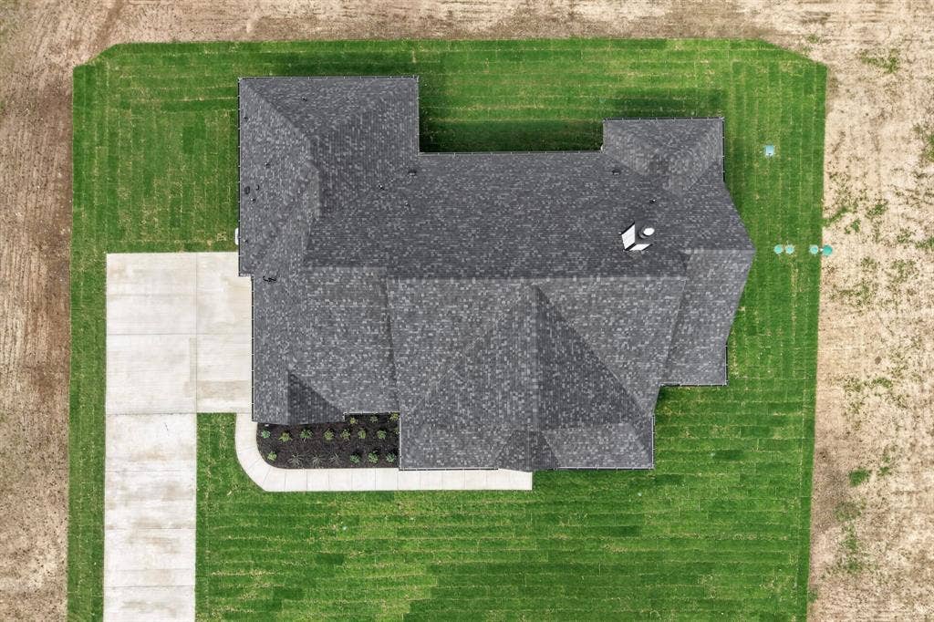 102 Nicklaus Drive, Sulphur Springs, TX 75482 Aerial perspective of the residence featuring a multi-gabled shingled roof, concrete driveway, concrete walkway, and landscaped planting beds
