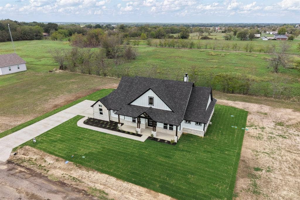 102 Nicklaus Drive, Sulphur Springs, TX 75482 Single-story residence featuring a steep-pitched roof, stone and board-and-batten siding, a covered front porch, and an attached concrete driveway