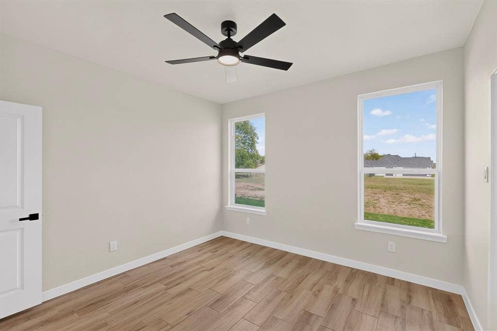 102 Nicklaus Drive, Sulphur Springs, TX 75482 Interior space featuring wood-finish tile flooring, matte black ceiling fan with integrated lighting, dual double-pane windows, and a panel door with matte black hardware