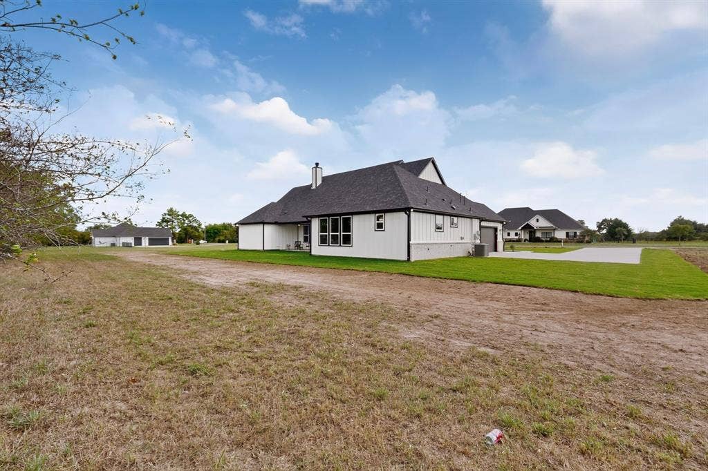 102 Nicklaus Drive, Sulphur Springs, TX 75482 Contemporary farmhouse exterior featuring white board-and-batten siding, a dark shingled roof, a chimney, and a concrete driveway