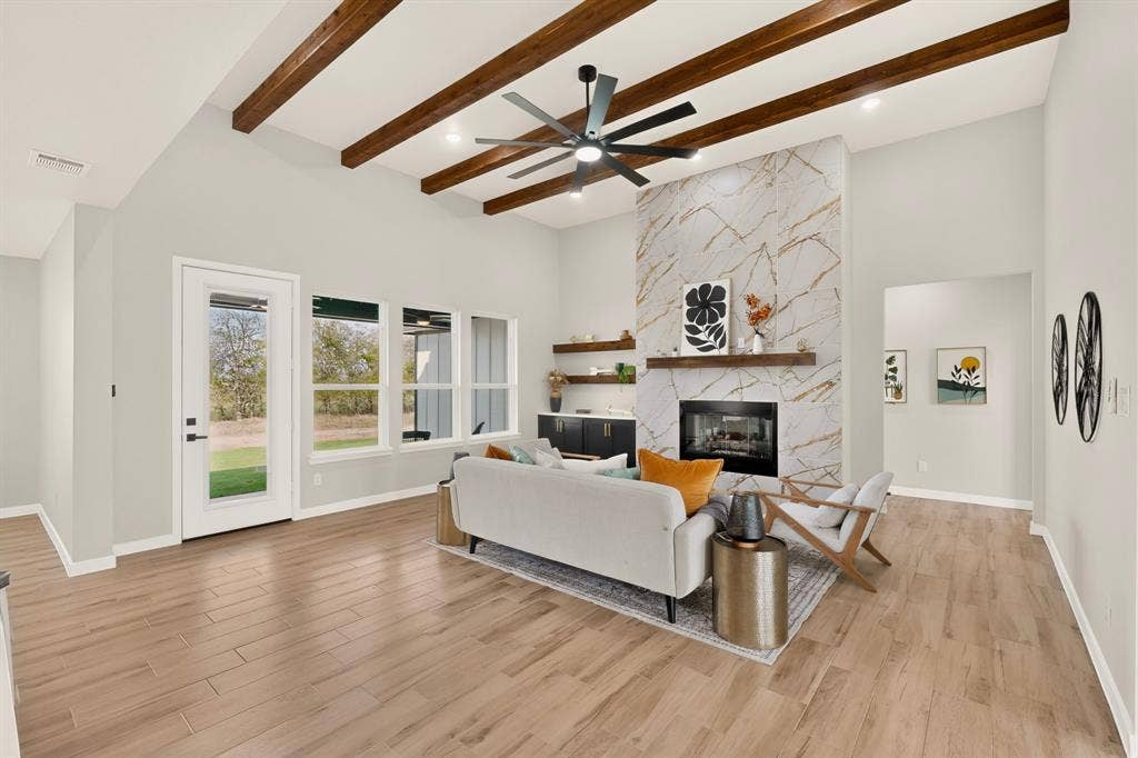 102 Nicklaus Drive, Sulphur Springs, TX 75482 Vaulted ceiling featuring exposed wood beams, full-height stone fireplace surround with a wood mantel, wood-finish flooring, and built-in cabinetry