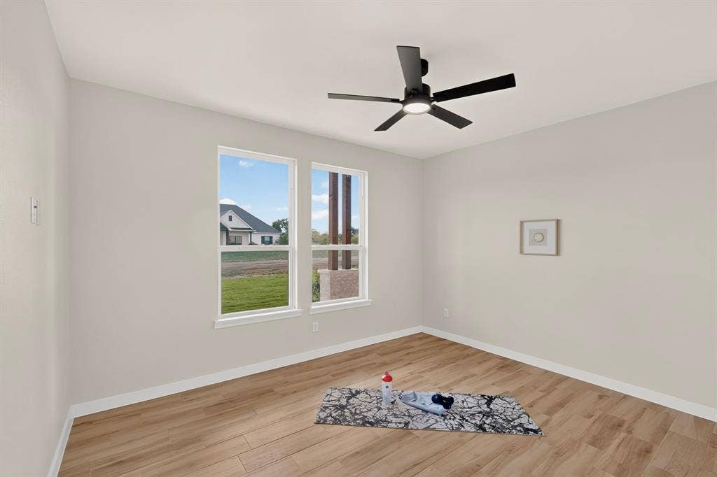 102 Nicklaus Drive, Sulphur Springs, TX 75482 Neutral interior space featuring wood-finish flooring, dual windows, and a matte black ceiling fan with integrated lighting