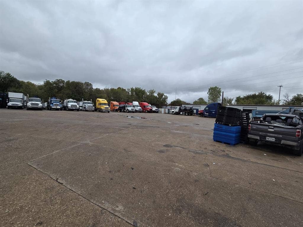 2311 Cartwright Street, Dallas, TX 75212 Expansive paved industrial lot featuring extensive open-air storage space and surrounding mature tree line