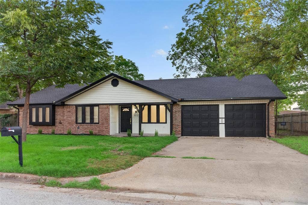 Single-story ranch exterior featuring a mixed masonry and horizontal siding facade, two-car garage with dark finish doors, covered front entryway, and dark window trim