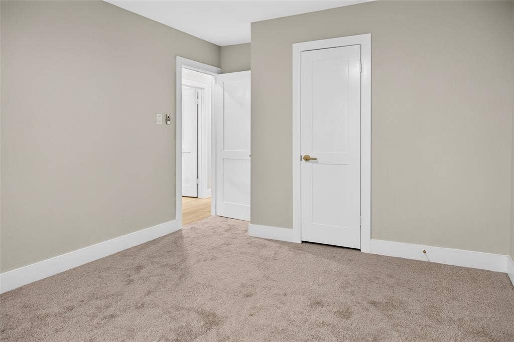 Neutral-toned interior space featuring wall-to-wall carpeting, white two-panel interior doors, and crisp white door casings