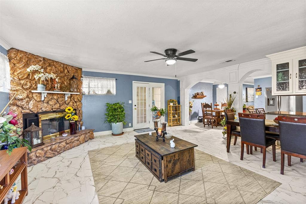 1801 Pleasant Run Road, Carrollton, TX 75006 Stone fireplace with an integrated mantel, arched architectural detailing, tile flooring, glass-paneled exterior door, and built-in upper cabinetry