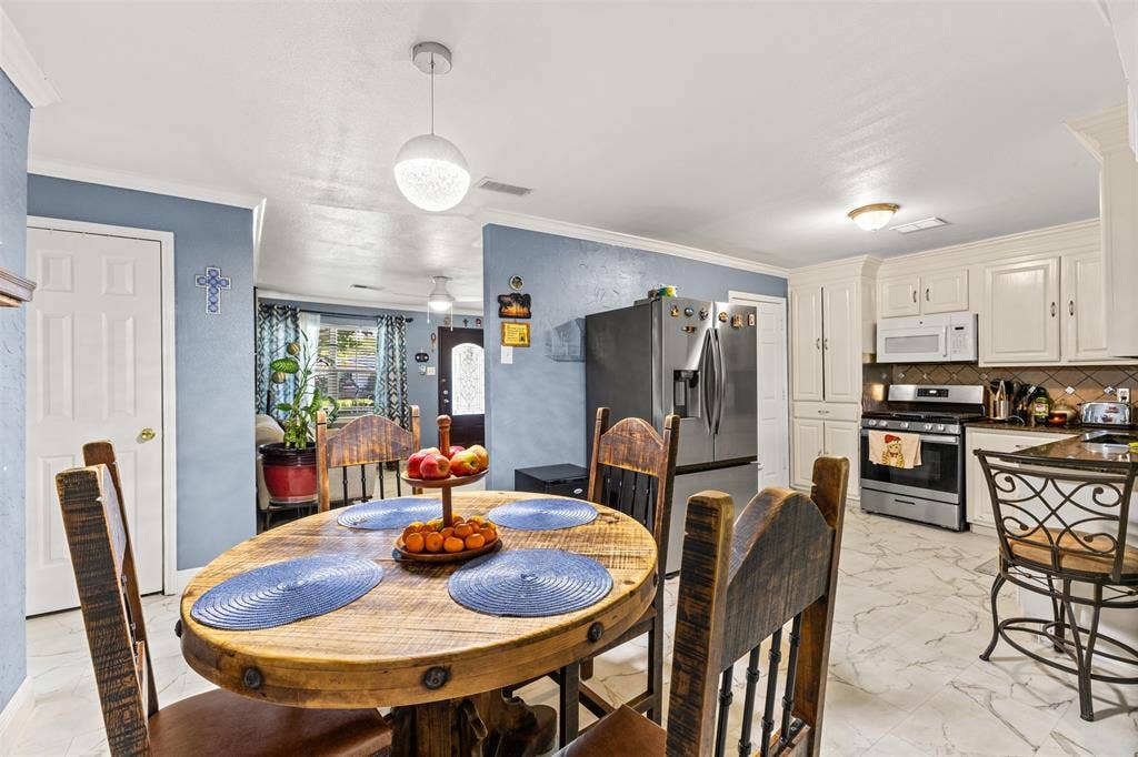 1801 Pleasant Run Road, Carrollton, TX 75006 Kitchen featuring white shaker-style cabinetry, stainless steel appliances, stone-look tile flooring, and a contemporary spherical pendant light