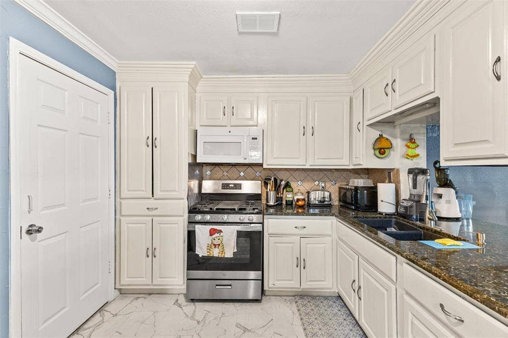 1801 Pleasant Run Road, Carrollton, TX 75006 Kitchen featuring white cabinetry, stone-finish countertops, stainless steel gas range, built-in microwave, and tile backsplash