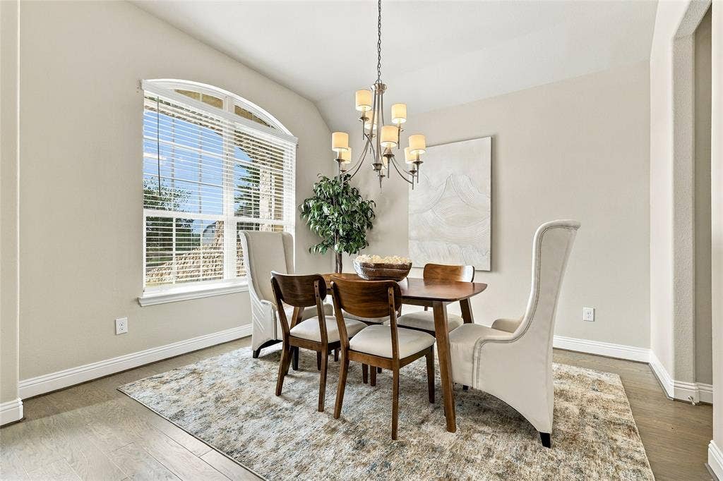 Dining area featuring wood-finish flooring, an arched window, and a multi-arm metal chandelier