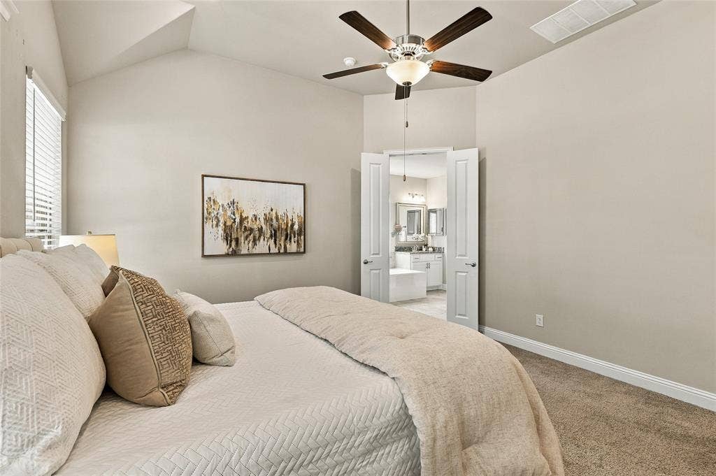 Vaulted ceiling featuring a central five-blade ceiling fan, wall-to-wall carpeting, and double-door entry