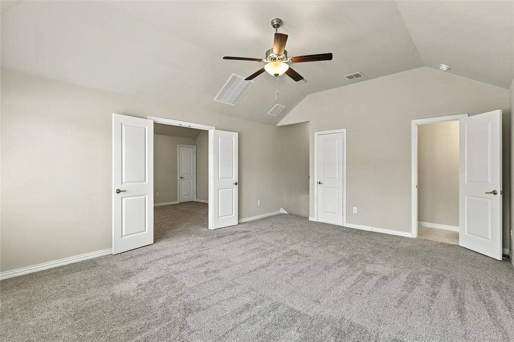 Vaulted ceiling featuring a ceiling fan with integrated lighting and neutral carpeting